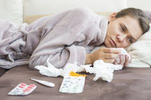 Sad woman with tissue and medicines lying on bed